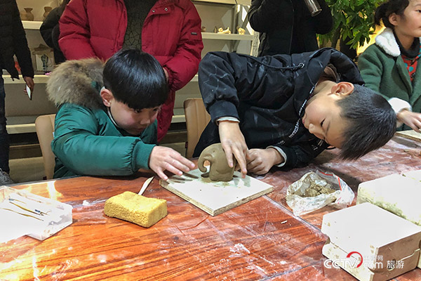 界首市博物馆内，孩子们在体验彩陶的制作过程